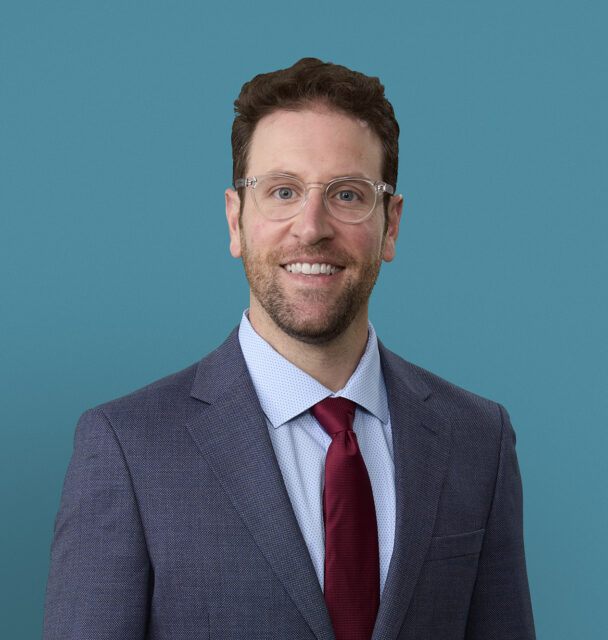 Professional headshot of Dr. Zachary Miller in gray suit with burgundy tie
