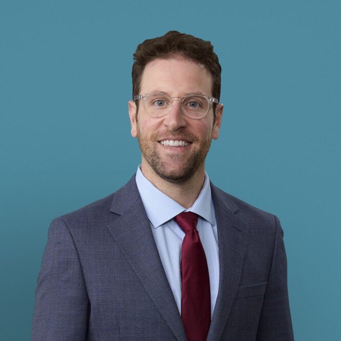 Professional headshot of Dr. Zachary Miller in gray suit with burgundy tie