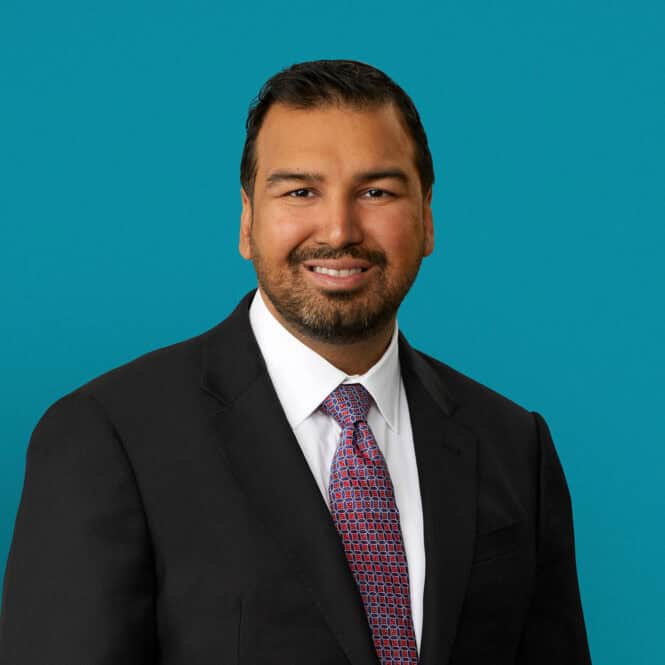Professional headshot of Dr. Zubin Agarwal in dark suit against turquoise background