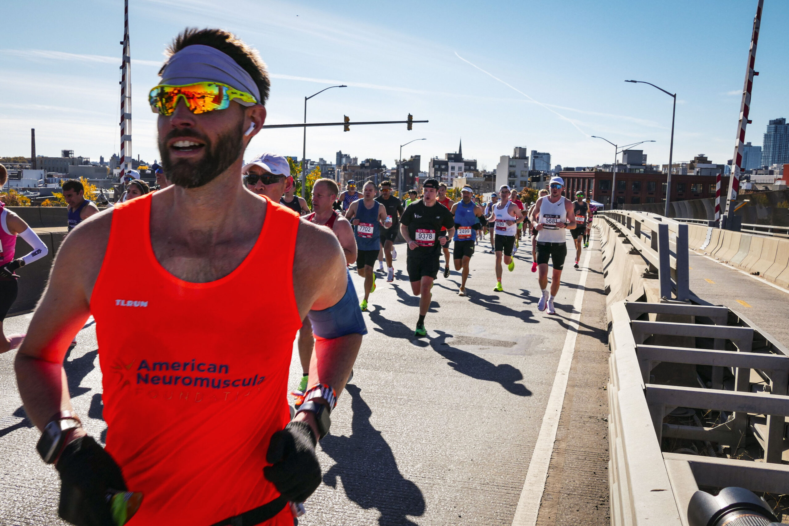 Runner in red American Neuromuscular tank top crossing bridge during marathon race