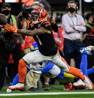 Football player in orange and black uniform catching ball while being tackled