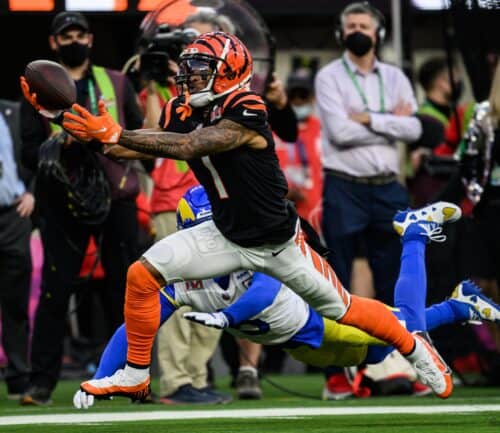 Football player in orange and black uniform catching ball while being tackled