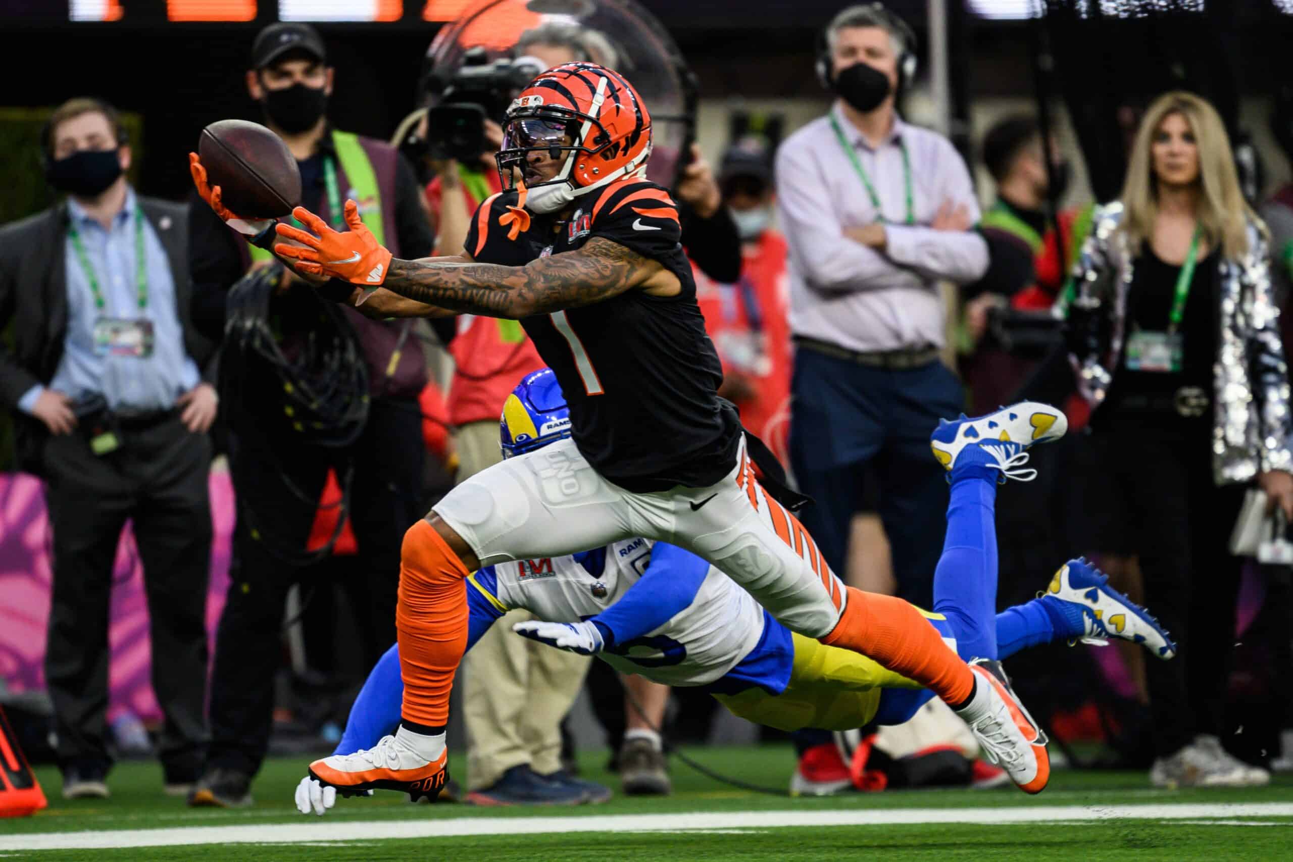 Football player in orange and black uniform catching ball while being tackled