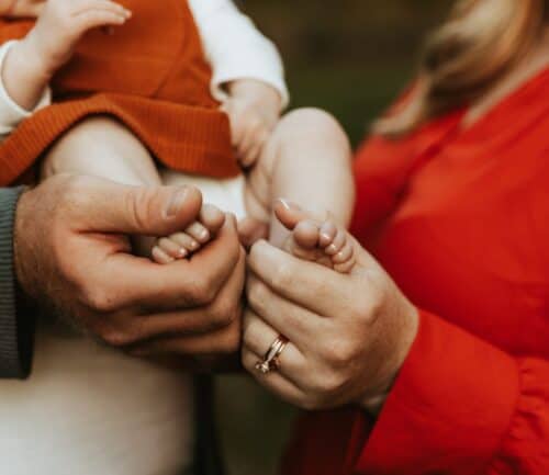 Parents gently holding their baby's tiny feet in their hands