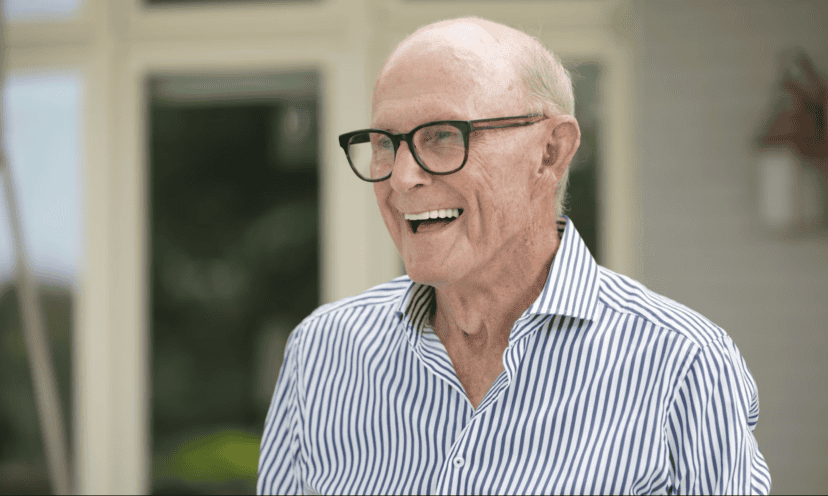 Smiling senior man with glasses in striped shirt outdoors at healthcare facility