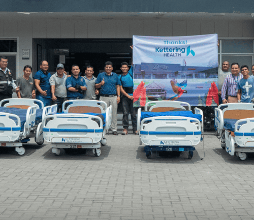 Group of healthcare workers posing with donated hospital beds from Kettering Health