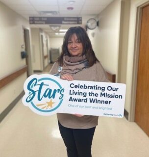 Andrea McKenna posing for picture with Living the Mission Award sign